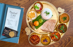 A thali of fortune card, a bill and a maharani thali from Prashad on a wooden table
